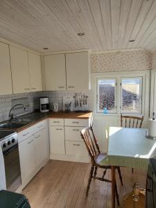 a kitchen with white cabinets and a table at Järnvägshotellet in Broddetorp