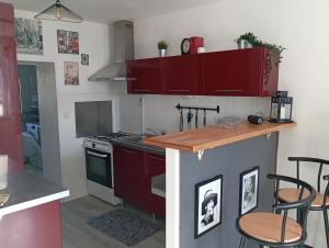 a kitchen with red cabinets and a counter with stools at La Petite Maison Cosy in Saint-Sauveur-le-Vicomte
