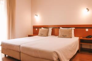 Postel nebo postele na pokoji v ubytování Vitoria Hotel