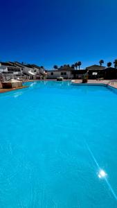 a large pool of blue water with buildings in the background at Sunny Bungalow with Pool & Patio in Sonnenland By Canarias Prime Homes in Maspalomas +10 photos