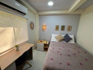 a bedroom with a bed with a desk and a window at Colorful Garden House in Providencia