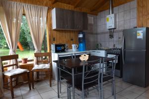 a kitchen with a refrigerator and a table with chairs at Cabañas Altos de carewe , Lican Ray chile in Licán Ray