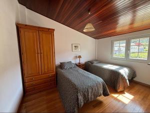 a bedroom with two beds and a wooden ceiling at Carnota Beach in Carnota