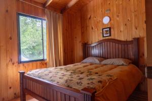 a bed in a wooden room with a window at Cabañas Altos de carewe 2, Lican Ray Chile in Licán Ray