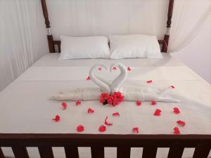 two white swans making a heart on a bed with roses at The Golden Sand Villa in Unawatuna in Unawatuna