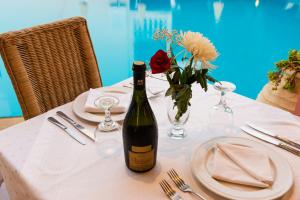 een tafel met een fles wijn en een vaas met bloemen bij Perla Marina Aparthotel in Ialyssos