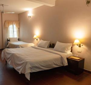 a hotel room with two beds with white sheets at Gama Heritage Residency in Cochin +26 photos