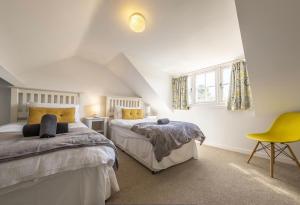 a bedroom with two beds and a yellow chair at Duffields House in Brancaster