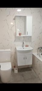 a white bathroom with a toilet and a sink at Parkside Residences in Tbilisi City