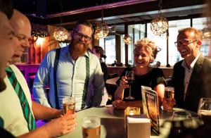 a group of people sitting around a table with drinks at Alpine Hotel by SnowWorld in Landgraaf