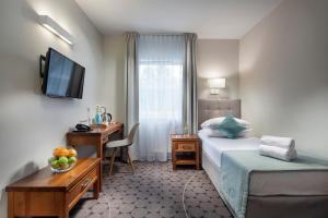 a hotel room with a bed and a desk and a television at Hotel Aqua Sopot - Destigo Hotels in Sopot