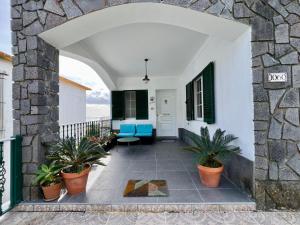 un arco que conduce a un porche con sillas y plantas azules en Vila Mandala, en Ponta Delgada