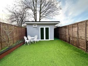 a backyard with a small house and a fence at Boutique Backyard Bungalow - Brimsdown in Enfield Lock