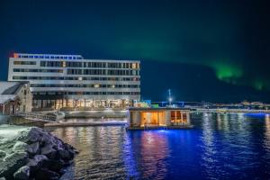 a hotel and a building on the water at night at Scandic Sortland in Sortland