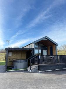 a small house with a porch and a building at Lodges at Moody Meadows in Llanarth
