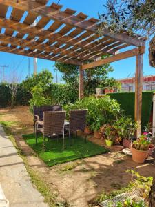 a patio with chairs and a table under a wooden pergola at Semelia & Maria's Guest Houses - Cozy Stay for 2 in Spata