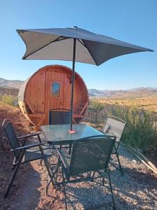 a table with an umbrella in front of a cabin at Ecoturismo El Refugio en La Colorada, Combarbalá in Combarbalá