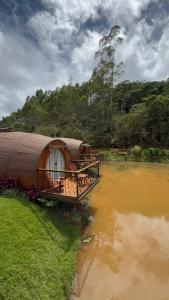 a large round house sitting on the side of a river at Chalés Villa Caravaggio in Santa Teresa