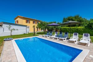 una piscina con sedie e ombrelloni accanto a una casa di Vila Rimanici, a wonderful and sunny pet friendly villa a Pićan