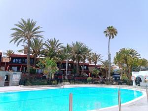 a swimming pool in front of a resort with palm trees at Schöne Wohnung Sun Club in Playa del Aguila