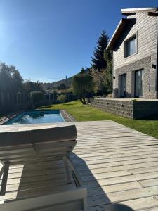 a wooden deck with a pool in front of a house at De los rios casa con pileta in San Carlos de Bariloche