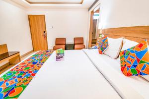 a hotel room with a large bed with colorful pillows at FabHotel Prime Royal Castle - Nr Coimbatore North Railway Station in Coimbatore