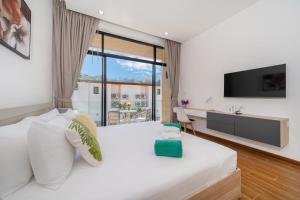 une chambre avec un grand lit blanc et une télévision dans l'établissement Goldena Twin Project - 3 Bedrooms Pool Villa, à Kamala Beach