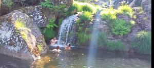 a group of people swimming in a waterfall at Tienda de Campaña en Ecoaldea Vegana Espiral en Plena naturaleza con comida y cena incluida in Passos +42 photos