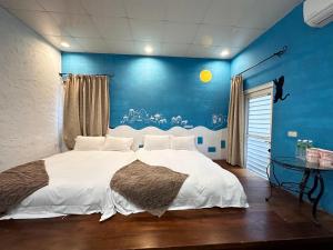 una camera da letto con un letto grande con una parete blu di 彤林溫泉民宿 a Jiaoxi