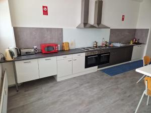 a kitchen with white cabinets and a red microwave at Hostel Terre in Fellbach