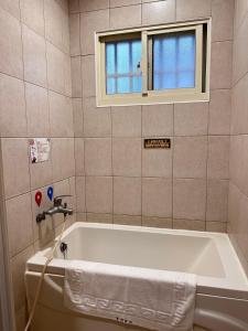 e bagno con finestra e vasca. di 彤林溫泉民宿 a Jiaoxi
