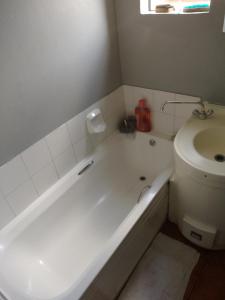 a bathroom with a white tub and a toilet at Houghton Luxurious Home in Johannesburg