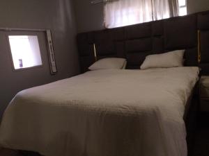 a bedroom with a large white bed with a window at Houghton Luxurious Home in Johannesburg
