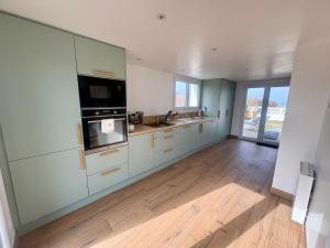 a large kitchen with white cabinets and a wooden floor at Maison face à la mer in Ouistreham