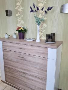 a wooden dresser with a vase of flowers on it at Bed & Breakfast Birgit Fröhlich in Gröst +10 photos