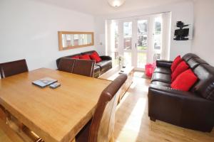 Una sala de estar con una mesa de madera y muebles de cuero. en The Sanctuary, en Sandown