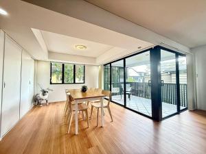 ブリスベンにあるKangaroo Point Stay - Being Everywhere at Once! Spacious 3 bedroom apartment, central location! Free carparkのテーブルのあるダイニングルームとバルコニーに犬がいる