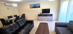 Una sala de estar con un sofá, una mesa y un televisor. en Holidays - Albufeira, en Albufeira
