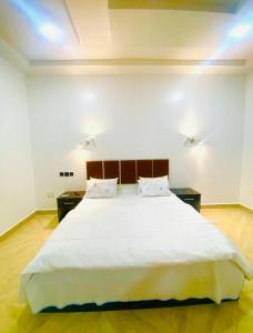 een slaapkamer met een groot wit bed en 2 tafels bij M2 Homes in Gwarinpa