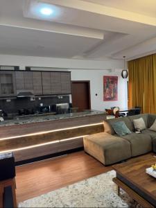 een woonkamer met een bank en een keuken bij M2 Homes in Gwarinpa