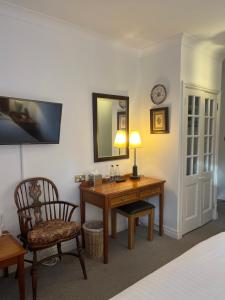 a bedroom with a desk and a chair and a mirror at Noel Arms - "A Bespoke Hotel" in Chipping Campden