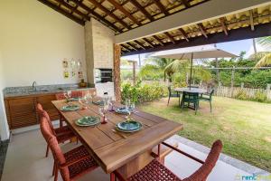 a wooden dining table with chairs and an umbrella at Ykutiba Imbassaí - Bangalô - J02 in Imbassai +46 photos
