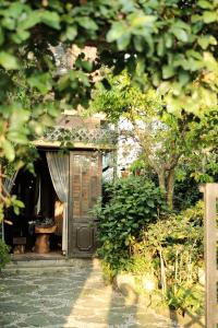 an entrance to a garden with a wooden door at Yesterday Homestay Hue in Thôn An Hòa