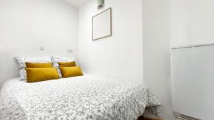 a white bedroom with a bed with yellow pillows at Le Avena - Centre Ville - Calme - Cour in Saumur
