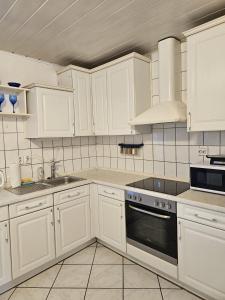 a kitchen with white cabinets and a stove top oven at Haus Mit Garten in Nürnberg