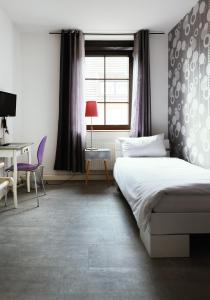 a bedroom with a bed and a desk and a window at Jül Boardinghouse in Jülich