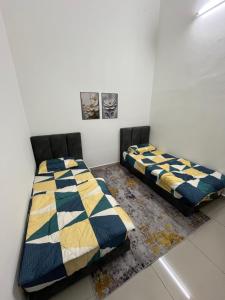 two beds sitting next to each other in a room at Roza Homestay in Kampong Parit Gantong