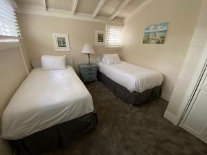 a bedroom with two beds and a lamp in it at Carmel Dolores Cottages in Carmel