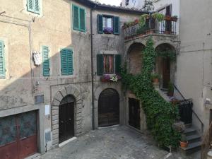 an old building with green shutters and a balcony at Giardino Bellavista Casa Vacanze in Castel del Piano