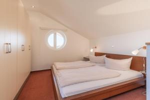 a bedroom with a white bed with a window at Eisvogel Classic 217 in Granzow